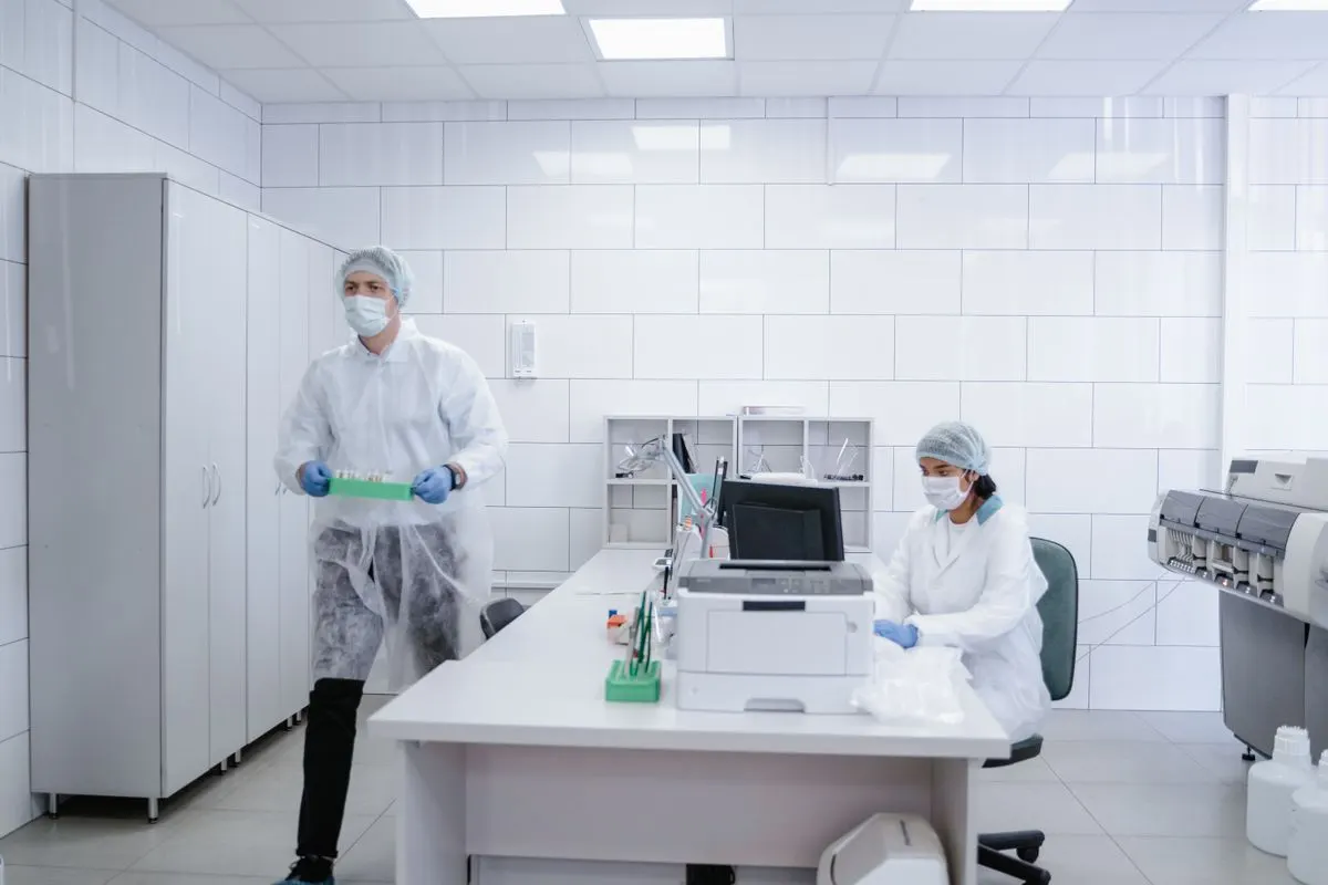 Gowned pharmaceutical operators in masks and gloves working in a controlled cleanroom, the largest source of microbial contamination